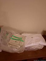 Folded white table cloth in plastic bag alongside fabric items
