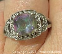 Cushion-cut iridescent stone ring with marcasite halo on finger