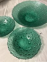 Three green bubble glass bowls of varying sizes on white background