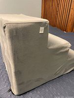 Side view of grey fabric-covered foam pet stairs showing three steps and removable cover