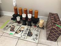 Full view of all items in the lot arranged on the floor, including candles on holders, shoe-themed wall plaques, and patterned suitcase.