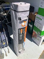 Full view of gray fabric carrying case packed with canopy tent, zippered closure and carrying handle visible