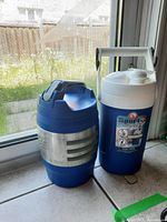 First photo showing both beverage coolers side by side on a windowsill with outdoor background.