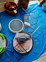 Lazy Susan wooden tray with curved multiple bowls, black and silver metal racks, white tray with rubber mat, pink napkin in plastic and black wire napkin holder on blue ground covering