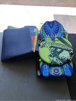 Image showing two folded foamy rubberized mats and two snow sleds stacked on pavement surface.