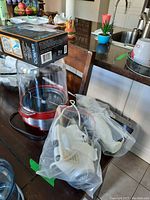 Photo showing the popcorn maker, mixer attachments in sealed plastic bags, and a box of Conair fabric defuzzer on top of the popcorn maker base.