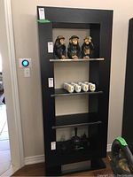 Front view of laminate shelving unit with four shelves, displaying decorative items (not included in sale). Visible chips to finish.