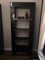 Photo of the laminate shelving unit with four metal shelves and dark laminate wood frame from the front showing the shelving and metal accents.