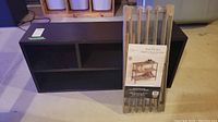 Wood laminate cubby organizer cabinet with two shelves, in dark color.
