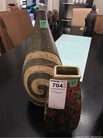 Two ceramic vases displayed on a table. The taller vase measures 17 inches and has a spiral design. The shorter vase measures 11 inches and has colorful patterns.