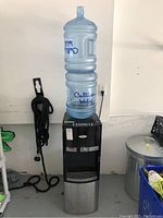 Full view of Whirlpool water cooler dispenser with Culligan water bottle on top, black and stainless steel body.
