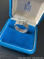 Front angle view of the decorative openwork ring nestled in blue velvet box