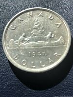 Reverse of coin showing Voyageur canoe, fur trader and Indigenous rower with 1947 date and maple leaf dot mintmark below