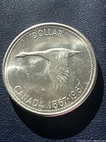 Front side of the coin showing flying Canada goose with inscriptions "DOLLAR" and "CANADA 1867-1967."