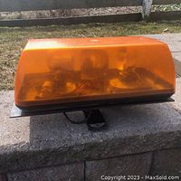 Front side view showing the amber plastic dome covering the rotating bulb light mechanism mounted on metal base.