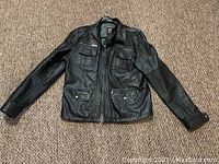 Front view of soft black leather ladies jacket showing full front side with zippered pockets, button details and buckle collar.