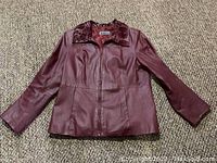 Front view of burgundy leather jacket with ribbon raised collar and zipper.