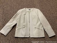 Front view of cream leather women's jacket showing zipper front, zippered pockets, and seam details.