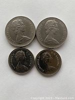 Four Canadian coins arranged with two one-dollar coins on top and two fifty-cent coins below, showing the obverse sides with Queen Elizabeth II portraits.