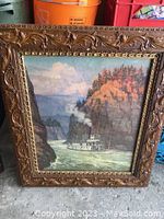 Full view of vintage framed print showing steamship in river canyon scene, ornate carved wooden frame visible around edges.