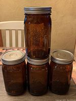 Front and top view of 4 amber Ball Elite quart jars with silver lids, arranged on a table.