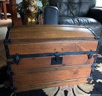 Front view showing curved top, latch and black metal straps.