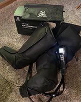 Photo of black air compression leg massager sleeves with wired LED controller, box and carrying bag with Bob and Brad branding.