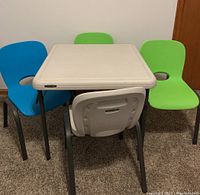 Full view of the 5-piece child's table and chair set, showing white folding table and four colorful chairs arranged around it.