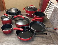 Photo showing full assortment of red nonstick cookware and mixing bowls on table.