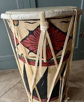 Front side view of hand painted dholak drum showing colorful folk art patterns and drumhead binding.