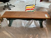 Front view showing length and depth of wooden bench with green base