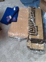 Three vintage wool blankets: one deep blue with satin trim and label, two tan blankets, one with geometric border, both in plastic bags.