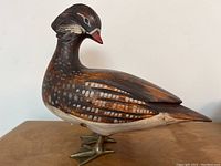Side profile of the hand carved and painted Mandarin duck figurine showing detailed feathering and brass feet.