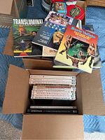 Two boxes of fantasy and erotic art books with colorful covers and Spectrum series volumes visible.