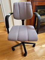 Front view of adjustable office chair with pink fabric upholstery, black armrests and black caster base.