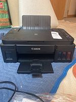 Front view of Canon Pixma G3200 printer with paper tray extended and ink tanks visible.