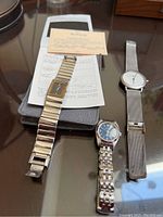 Photo showing three wristwatches: Seiko with warranty certificate and case, Calvin Klein with mesh band, and Timex with linked band.