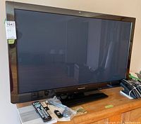 Front view of Panasonic Viera 42-inch plasma HD television on wooden surface with remote and wireless adapter displayed.