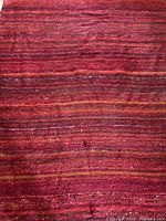 Overall view of red silk carpet with horizontal stripes