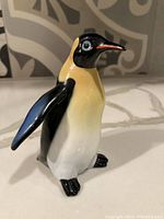 Front side view of the porcelain penguin figurine highlighting the detailed painting and glossy finish.