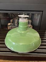 Side and top view of green enamel ceiling light fixture showing glossy green exterior and attached mounting wire.