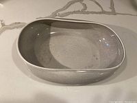 Side view of the vintage rectangular dish showing the smooth round edges and grey glaze.