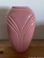 Front view of pink ceramic vase showing embossed decorative pattern and glossy surface.