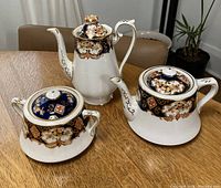 Set of two tea pots and one sugar bowl on wooden table showing full set and design