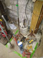 Six car jacks and pole stands arranged on a concrete floor against a cinder block wall, showing various colors and types of metal stands and jacks.