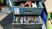 Metal cabinet with two drawers open showing various hand tools including files and screwdrivers