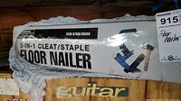 Photo of sealed box showing Central Pneumatic 2-in-1 cleat/staple floor nailer with partial view of packaging tear.