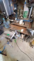 Metal work bench with attached vise on front right and sander on left. Clamps and various items on top and around bench.