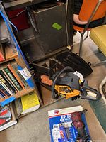 Poulan Pro chainsaw with yellow and black casing along with black blade cover, placed near a bookshelf and boxes.