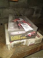 Photo showing boxed Chicago Electric reversible drill and two boxes of framing nails on a wooden surface in a basement.